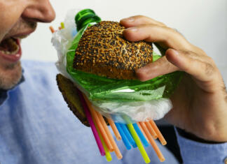 Nova metoda za odstranjevanje mikroplastike A man eats a burger made from a tasty bun with sesame and poppyseed filled with different types of disposable plastic. The concept of disposable plastic as a danger for ecology and human health.