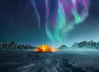 Kje, kdaj in kako lahko opazuješ severni sij A tent pitched up in snow at night with the northern lights flickering in the sky above. Aurora Borealis and travelling. Photo composite.