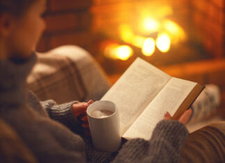 Seznam odličnih knjig za praznično branje book and cup of coffee in hands of girl on winter autumn evening near fireplace