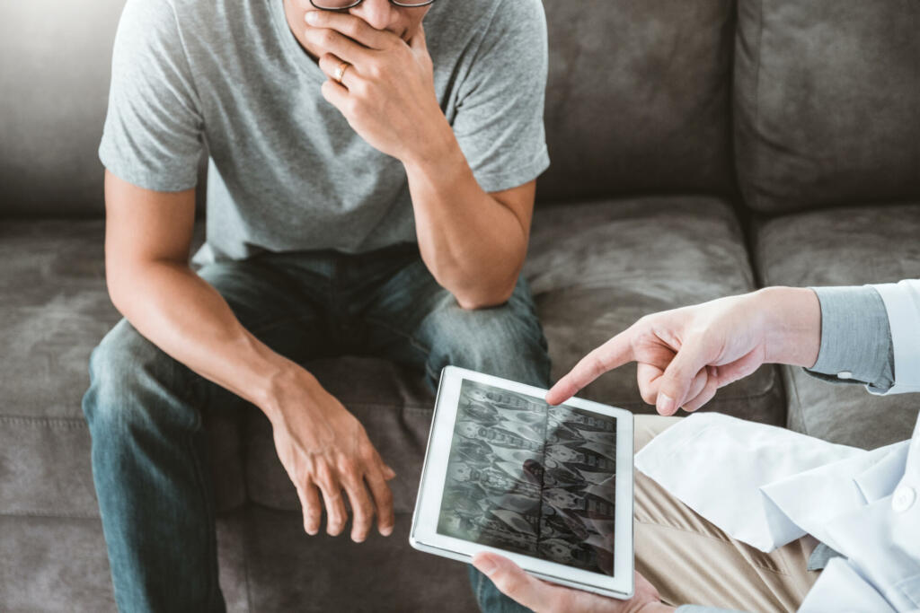 Doctor consulting diagnostic examining with patient presenting X-ray film results on digital tablet Visit the patient's home