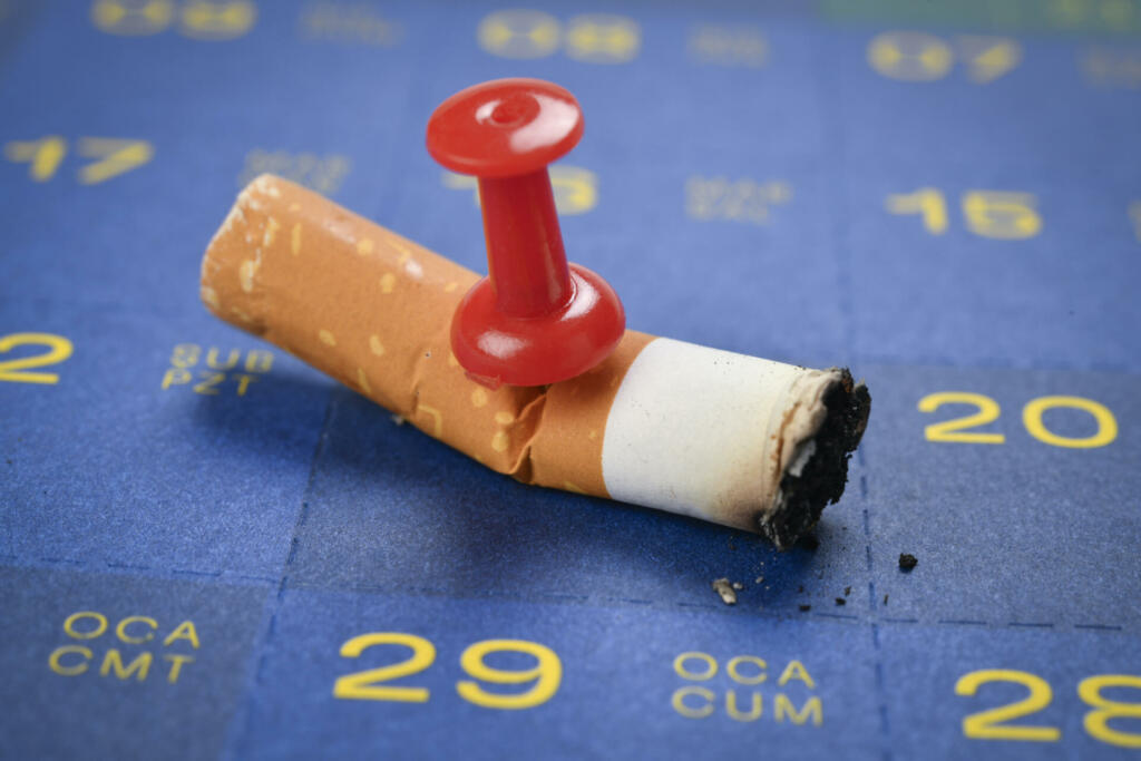 Finished cigarette on calender reminding time to quit smoking