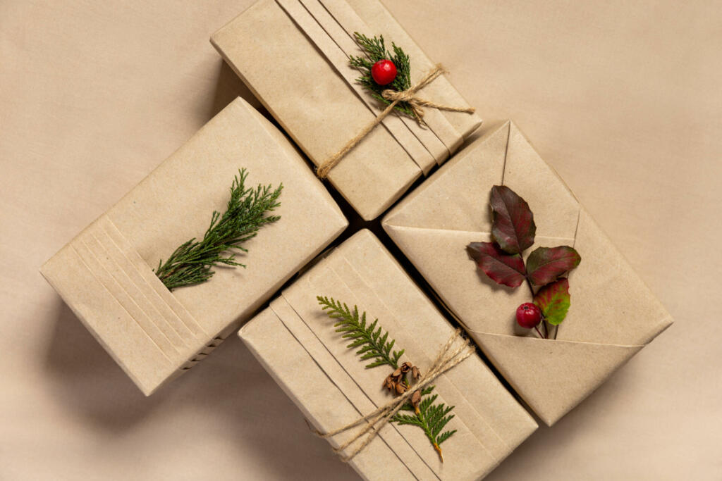 Four Christmas gift boxes, trendy kimono style with eco-friendly materials. Craft brown paper with folds and natural twigs and berries on linen textile background