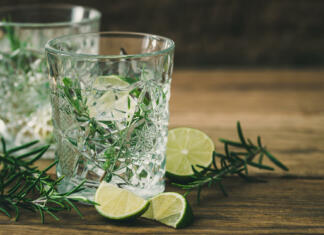 Kuhan gin recepti: 3 super recepti za kuhan gin Glasses with a refreshing lime rosemary drink, lime halves and rosemary branches on old wood