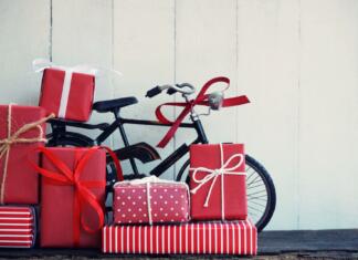 Darilo za kolesarja: Najboljša božična darila za kolesarje Group of elegant red gift box stack decorated with vintage toy bicycle on wood background, vibrant valentine lovely present concept, copy space