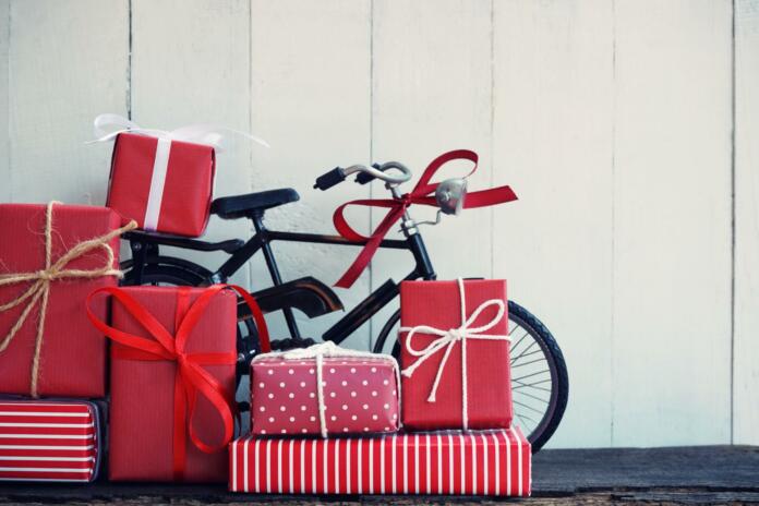 Group of elegant red gift box stack decorated with vintage toy bicycle on wood background, vibrant valentine lovely present concept, copy space