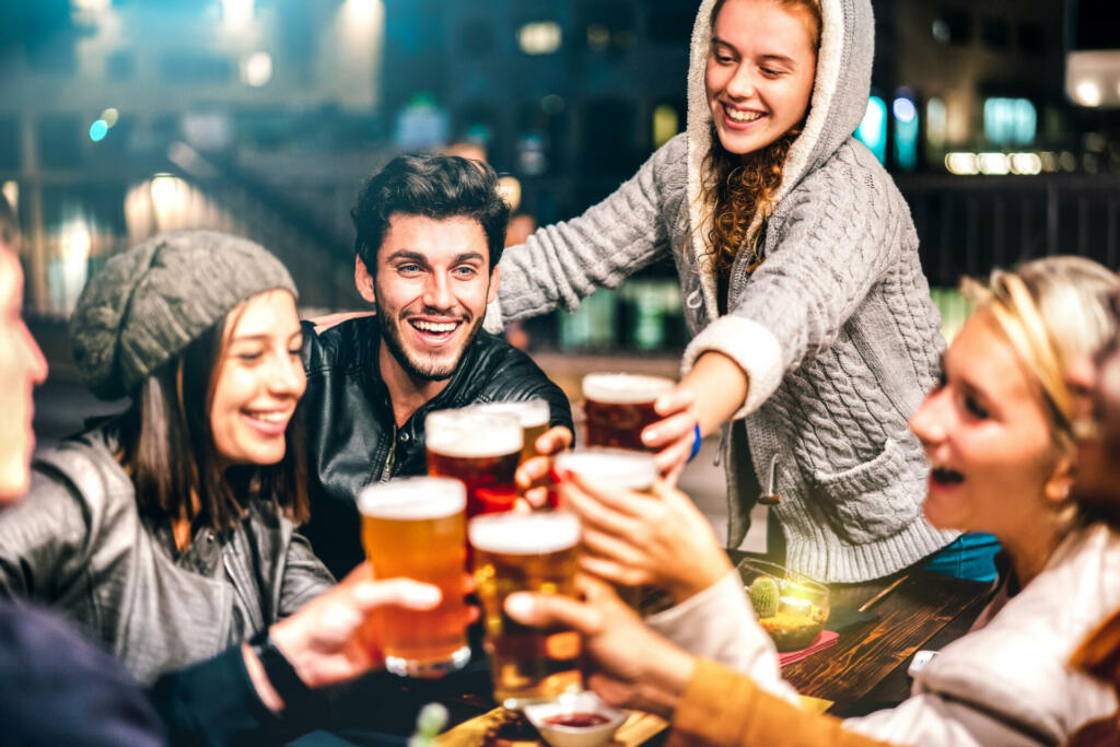 Happy people drinking beer at brewery bar out doors - Multicultural life style concept with genuine friends enjoying time together at open air restaurant patio - Vivid filter with focus on guy