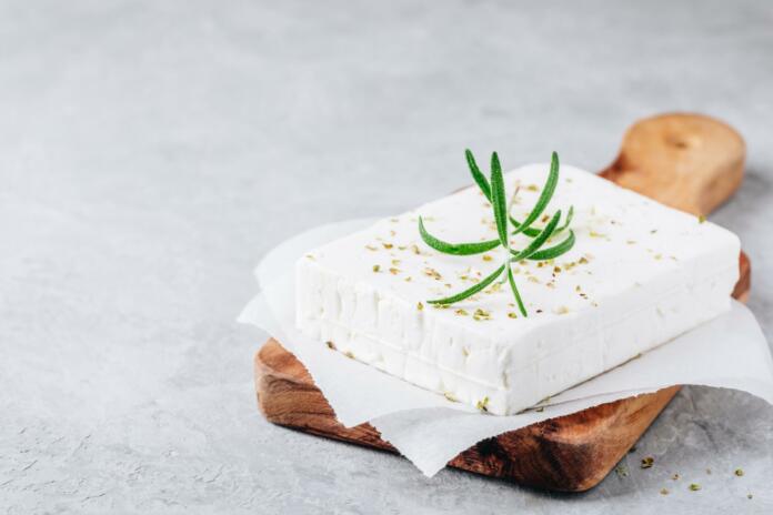 Homemade greek cheese feta with rosemary and herbs on wooden cutting board