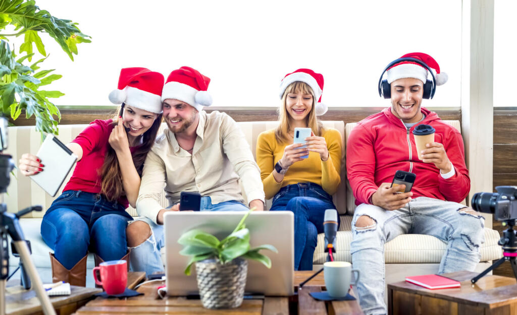 merry christmas! Young group of friends celebrating xmas time wearing santa claus hat on live streaming network online interacting with tech. fun, social media and lifestyle concept on winter holidays