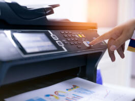 Office worker print paper on multifunction laser printer. Copy, print, scan, and fax machine in office. Modern print technology.  Photocopy machine. Document and paper work. Professional scanner.