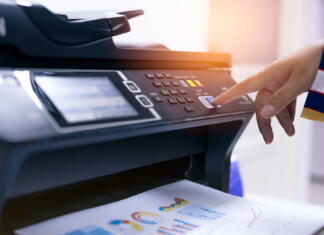 Najem tiskalnika: Poraba in cena Office worker print paper on multifunction laser printer. Copy, print, scan, and fax machine in office. Modern print technology. Photocopy machine. Document and paper work. Professional scanner.