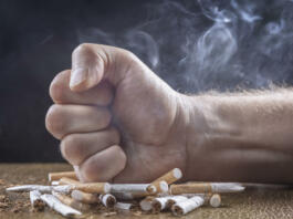 Quit smoking man fist crushing cigarettes stop smoking concept on dark background