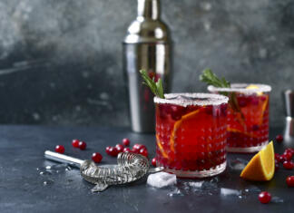 Top 7 koktajlov za zimo: Zimski koktajli, ki jih lahko narediš sam Red christmas cocktail with cranberries and oranges in a glasses on a dark slate, stone or concrete background