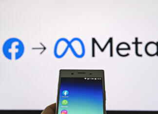 Velika izguba za Meto Smartphone display with logo of Facebook, WhatsApp and Instagram apps in hand against blurred META logotype on white monitor background: Tallinn, Estonia - October 29, 2021