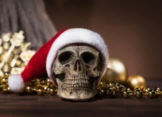 5 božičnih grozljivk za praznični ogled Still life with santa claus skull with gold christmas balls and golden ornament with copy space, Merry xmas and Happy new year concept