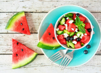 Si vedel, da barva krožnika vpliva na lakoto? Watermelon salad with cucumber, blueberries and feta cheese. Top view table scene on a white wood background.