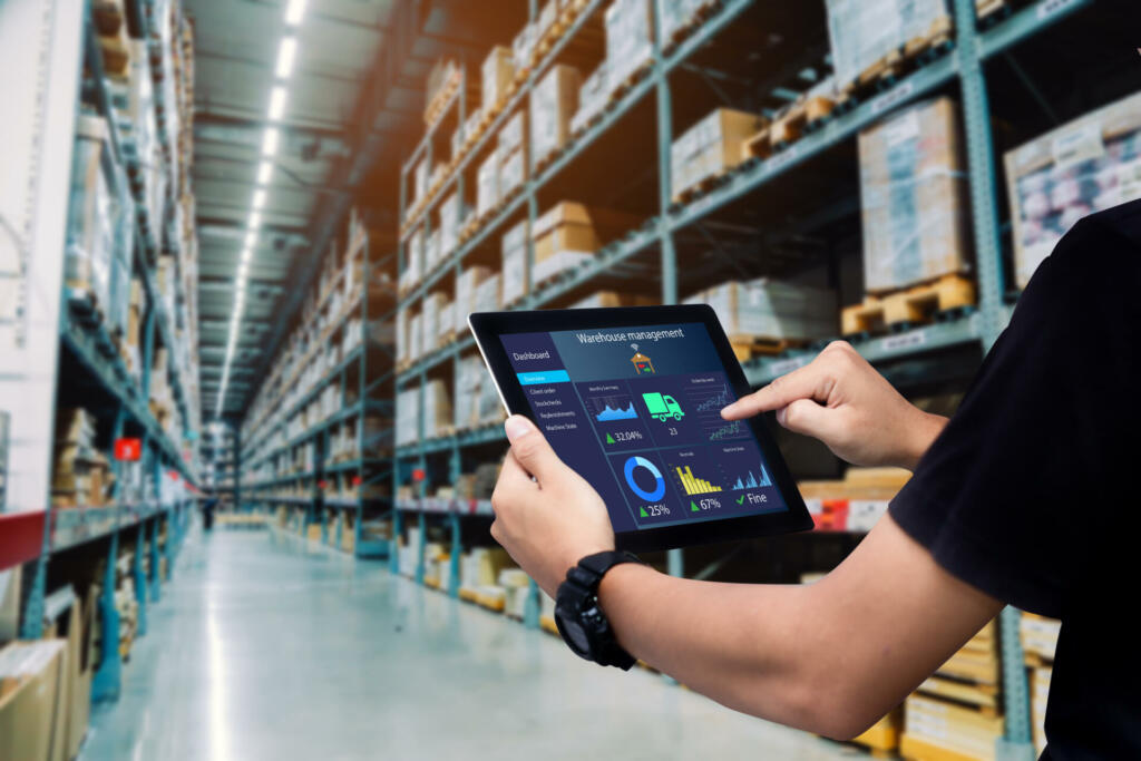 Worker hands holding tablet on blurred warehouse as background