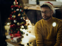 Young pensive man feeling lonely while spending New Year's eve alone at home.