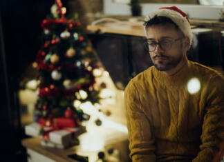 Ta »veseli« mesec ali vidik decembra, ki ni prazničen Young pensive man feeling lonely while spending New Year's eve alone at home.