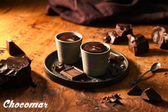 Skodelici vroče čokolada na pladnju, okoli so kosi temne čokolade