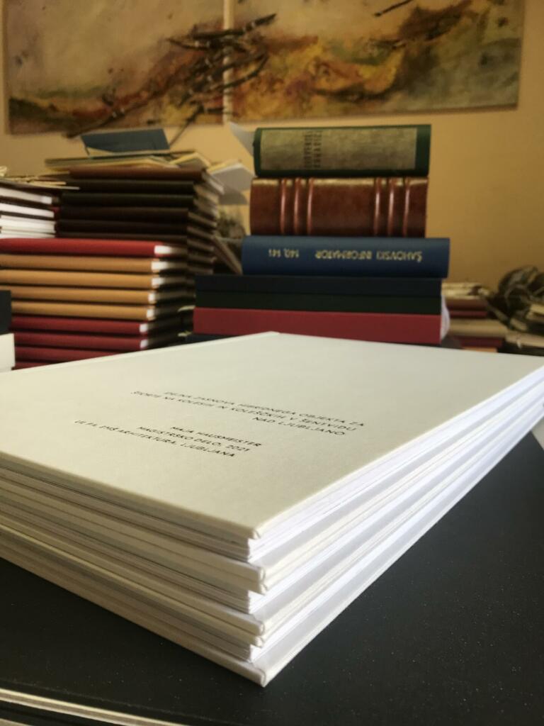 Listi diplomske naloge, v ozadju so knjige