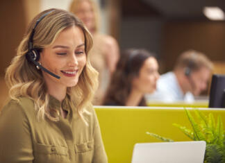 Tržnik: Pridruži se nam kot tržnik oglasnih kapacitet spletnih in tiskanih medijev (M/Ž) Businesswoman In Cubicle Wearing Headset Talking To Caller In Busy Customer Services Centre