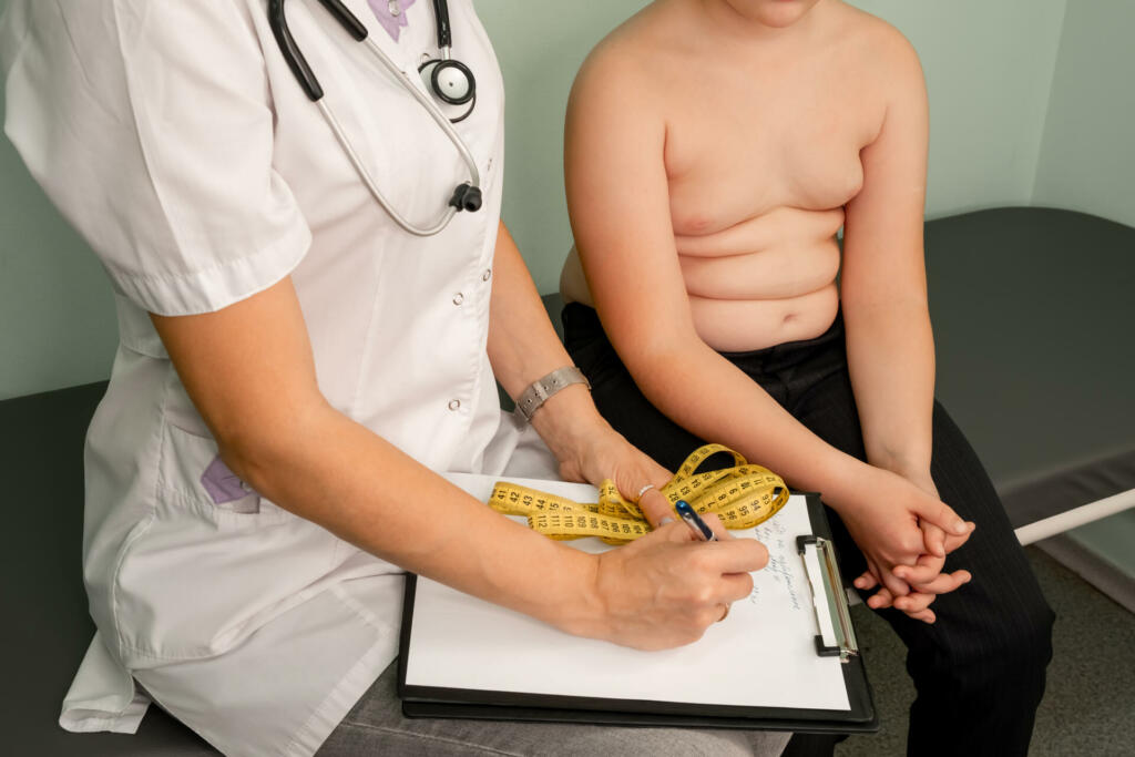 Childhood obesity problem and weight loss. Fat boy at a nutritionist appointment. Overweight boy consulting with doctor in office. Doctor examining fat boy in clinic. Doctor measuring overweight boy.