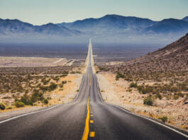 Classic panorama view of an endless straight road running through the barren scenery of the American Southwest with extreme heat haze on a beautiful hot sunny day with blue sky in summer