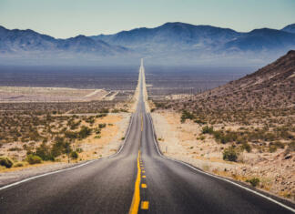 Najnižje kopenske točke sveta Classic panorama view of an endless straight road running through the barren scenery of the American Southwest with extreme heat haze on a beautiful hot sunny day with blue sky in summer