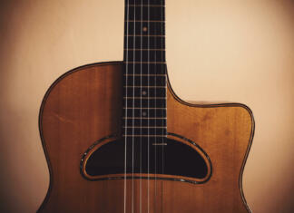 Zakaj je Django Reinhardt morda najboljši kitarist vseh časov? Closeup view of an old manouche acoustic guitar, vintage style.