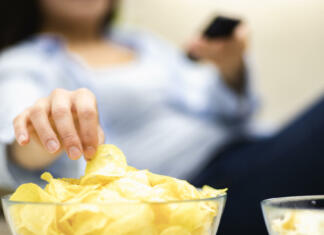 Kaj je gen »nemogoče je pojesti samo en čips«? Concept take potato chips with you to watch movie. Close up. Blurred background.