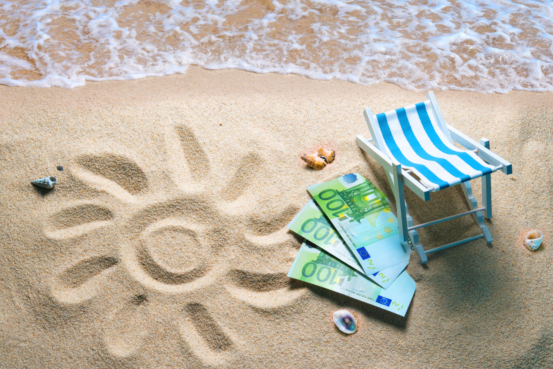 Deckchair with euro bills on a beach with a sun drawn on the sand. Travel money savings concept