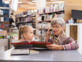 Grandmother reads a book to her granddaughter at the library