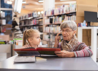 Največkrat izposojene knjige leta 2022 Grandmother reads a book to her granddaughter at the library