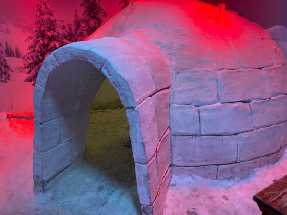 igloo and snow shelter in high snowdrift with mountains peaks on background.