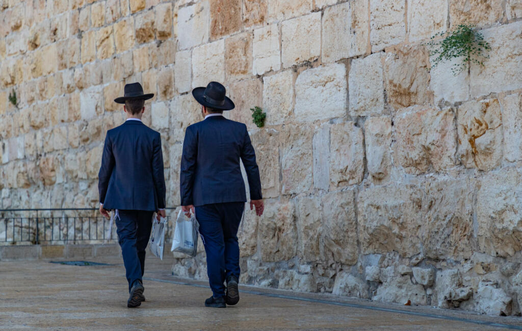 Jerusalem, Israel - June 16, 2019: A picture of two Jewish men walking next to the Old City walls (Jerusalem).