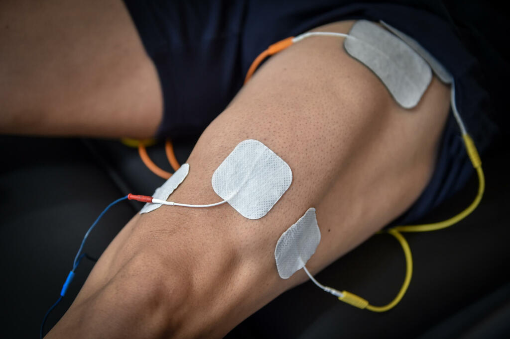 Muscle stimulator device with electrodes applied to quadriceps by a professional physiotherapist