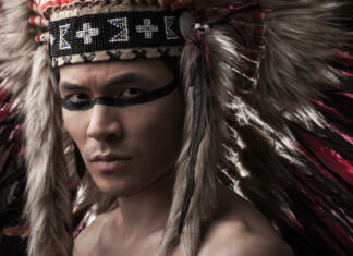 Najdene najstarejše konice v zgodovini Naked indian strong man with traditional native american make up and headdress looking at the camera. Close up desaturated studio shot