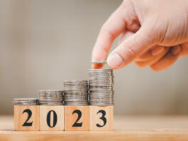 New year 2023 with coins stacking by hand for saving money and financial planning concept