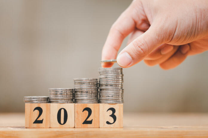 New year 2023 with coins stacking by hand for saving money and financial planning concept