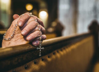Delež katolikov v Sloveniji pada – kakšna je prihodnost Cerkve? Praying senior hands with rosary in church bench
