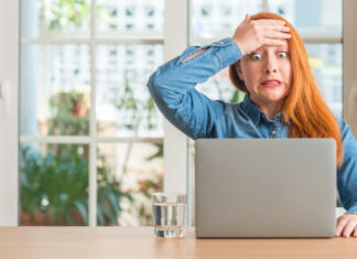 Ki ali kateri? Katera beseda je pravilna? Redhead woman using computer laptop at home stressed with hand on head, shocked with shame and surprise face, angry and frustrated. Fear and upset for mistake.