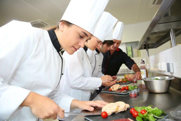 Team of young chefs preparing delicatessen dishes