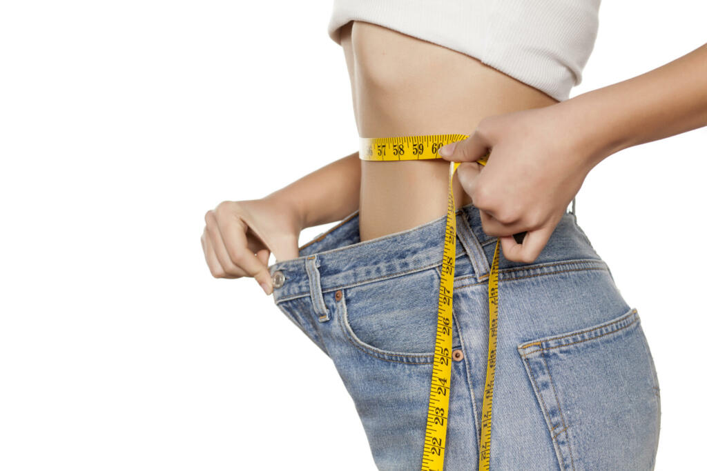 woman posing with a measuring tape and a big size pants