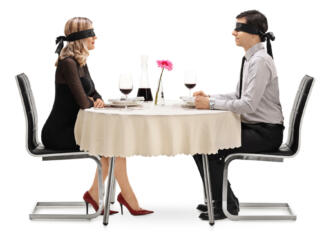 Kako se zavarovati na zmenku na slepo? Young man and woman on a blind date seated at a restaurant table isolated on white background