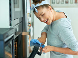 Young woman cleaning oven in the kitchen. High quality photo