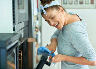 Young woman cleaning oven in the kitchen. High quality photo
