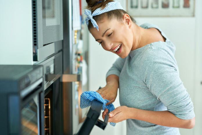 Young woman cleaning oven in the kitchen. High quality photo