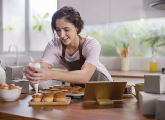 Slovenija s 50-odstotnim širjenjem vajeniških programov Young woman pouring cream on the cupcake in the kitchen