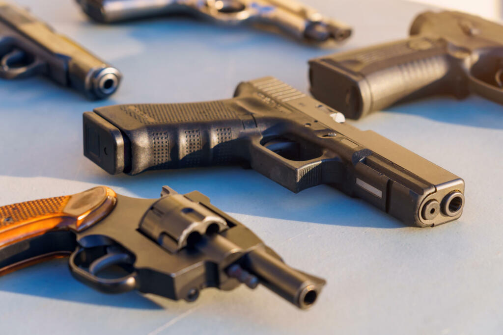 A gun on the table among the weapons, selective focus. Crime news background. The concept of rules for the owners of firearms. Shooting training. Confiscation of contraband and illegal carrying.