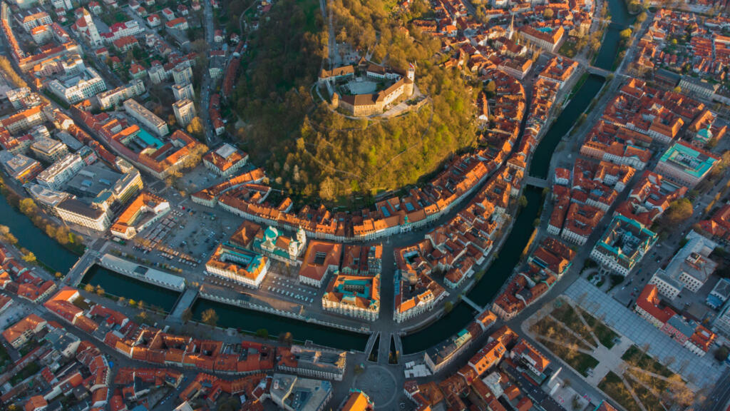 Pogled s ptičje perspektive na hrib z gradom, ki ga obdaja reka in mesto